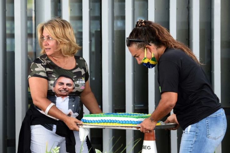 Supporters of Brazilian President Jair Bolsonaro carry a cake on the lawns of the Alvorada Palace to celebrate his birthday, in Brasilia