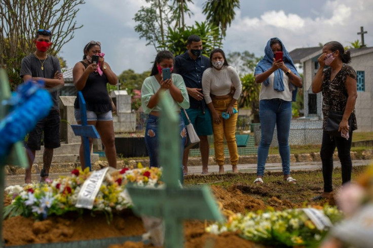 Relatives of a Covid-19 victim attend a funeral in Brazil, where the daily death toll is soaring