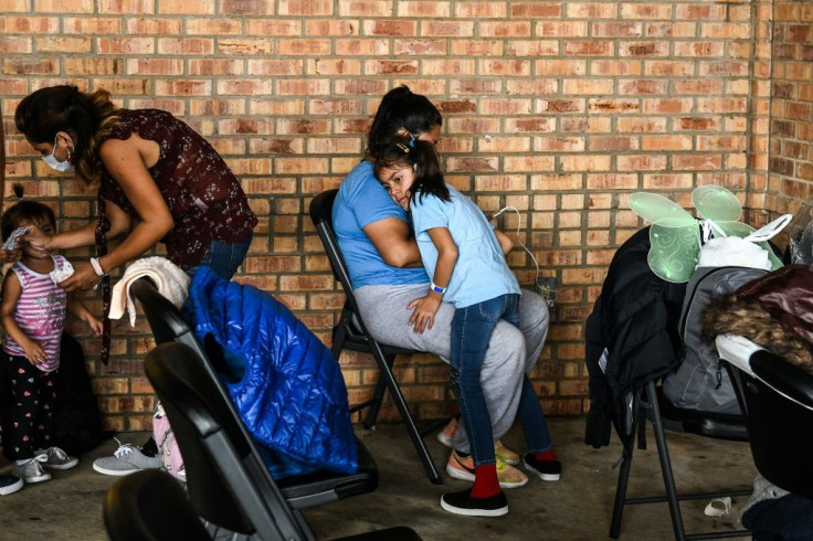 A migrant girl from Central America waits with her mother for a bus after they are dropped off by the US Customs and Border Protection near the Gateway International Bridge between Brownsville, Texas, and Matamoros, Mexico, on March 15, 2021