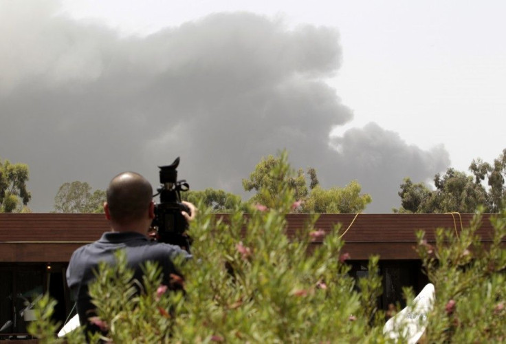 A journalist films from the roof of a hotel as smoke rises in the sky in Tripoli