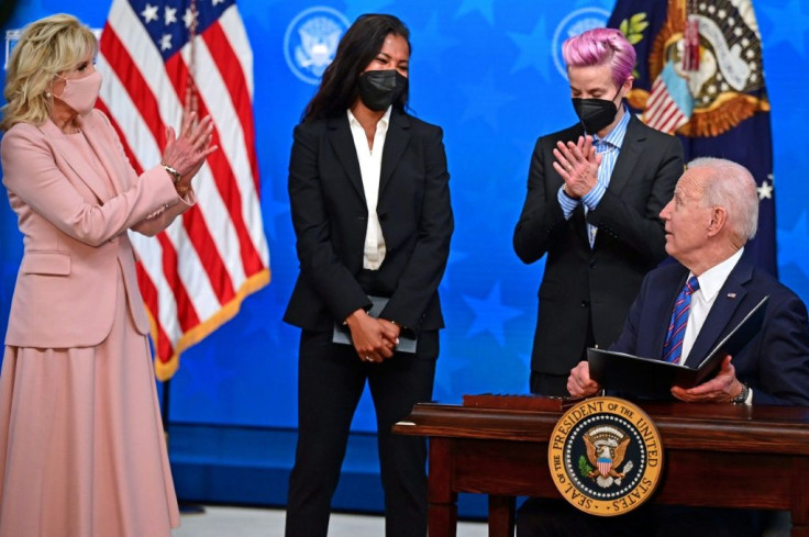 US President Joe Biden, with (L-R) his wife Jill Biden and US soccer stars Margaret Purce and Megan Rapinoe looking on, signed a proclamation on Equal Pay Day 2021