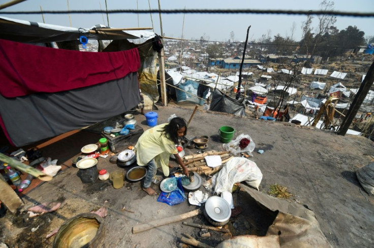A Rohingya refugee child arranges utensils in a temporary shelter