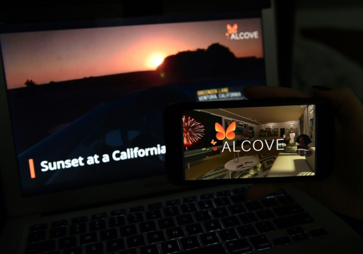 This illustration picture shows a virtual road trip on a computer and the travel application logo from Alcove VR displayed on a smartphone