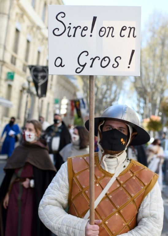 A man wearing a period costume, holds a placard reading "Sire! we are fed up" during a demonstration in southern France