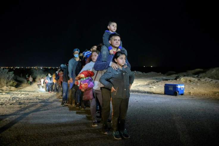 A family of immigrants stand in line with others at a processing checkpoint before being detained at a holding facility by US Border Patrol agents in the Texas border city of Roma