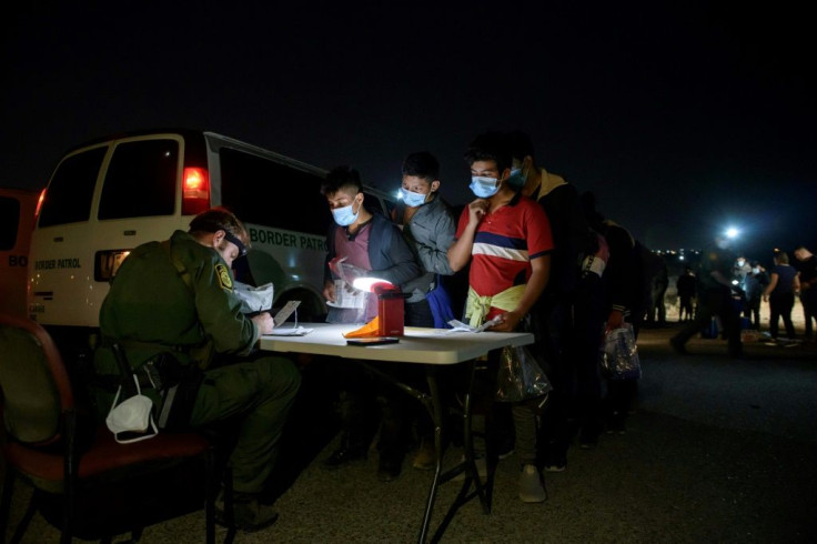 Children and adolescents are processed at a makeshift 'office' by a Border Patrol agent after reaching Roma, Texas late on March 27, 2021