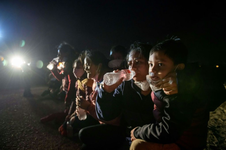 Women and children drink water and wait to be processed by US Border Patrol agents after crossing the Rio Grande from Mexico to Texas
