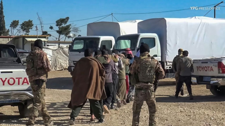 Kurdish YPG forces march off men towards vehicles during a security operation at the Kurdish-run Al-Hol camp in northeast Syria