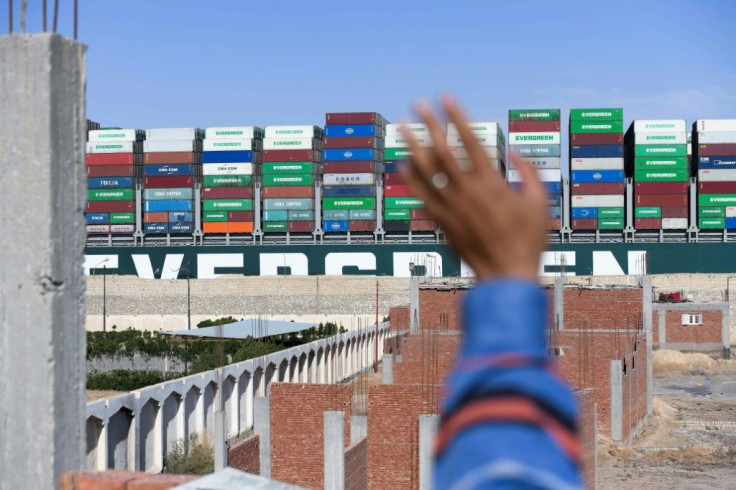 A man waves at the Panama-flagged MV 'Ever Given' container ship as it is tugged in Egypt's Suez Canal after it was fully dislodged from the banks