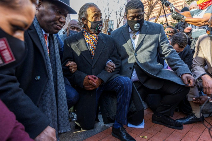 Lawyer Ben Crump (left), the Reverend Al Sharpton (C) and relatives of George Floyd take a knee in Minneapolis on March 29, 2021