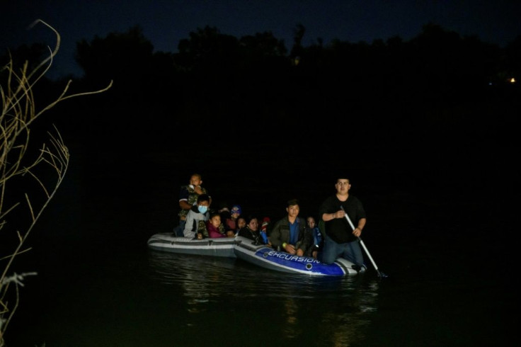 A Mexican people trafficker rows a small boat across the Rio Grande carrying Guatemalan and Honduran migrants from Miguel Aleman, Mexico, to Roma, Texas, March 28, 2021