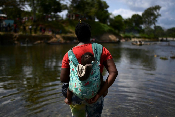 A migrant carrying a baby crosses the Chucunaque river after walking for five days in the Darien Gap