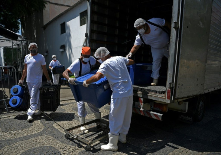 Workers unload food from a truck at a food distribution center in Rio de Janeiro, Brazil, on March 24, 2021