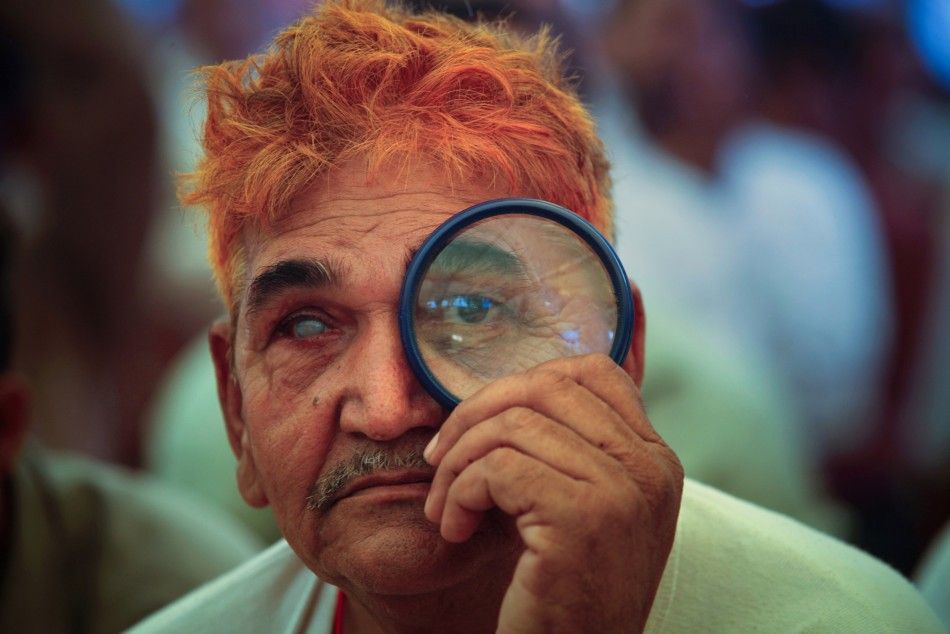 A supporter of India039s yoga guru Ramdev uses a magnifying glass to watch his address at Ramlila grounds in New Delhi