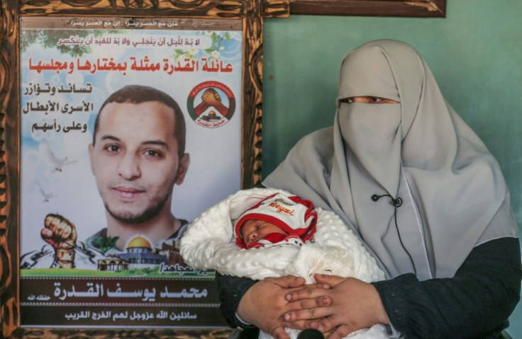 Iman al-Qudra, wife of Palestinian prisoner Mohammad, seen in the poster, holds their newborn boy, conceived with his smuggled sperm