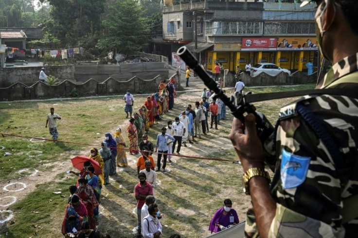A paramilitary guard watches as people wait to vote at a polling station during state elections in South 24 Parganas district, about 70 kilometres from Kolkata, India