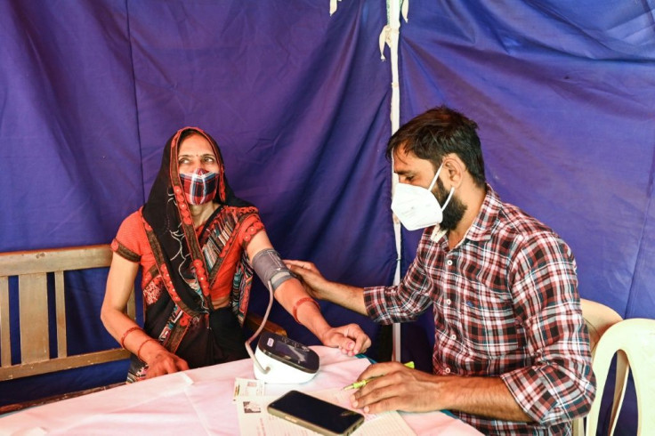 A medical worker checks the blood pressure of a woman before she is vaccinated
