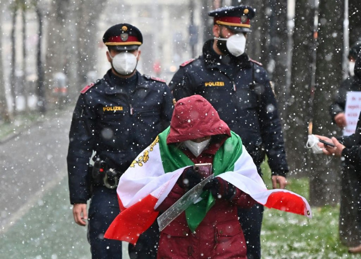 Policemen walk behind an Iranian opposition  protester who took part in a rally against the Tehran government near the international Iran nuclear talks in Vienna