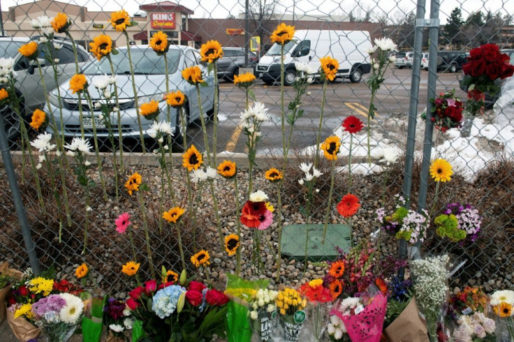 Flowers hang from the perimeter fence outside a King Soopers grocery store in Boulder, Colorado on March 23, 2021, one day after a mass shooting left ten dead, including a Boulder police officer