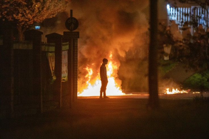A person stands in front of the flames in Newtownabbey, Befast on April 3, during a week of rioting