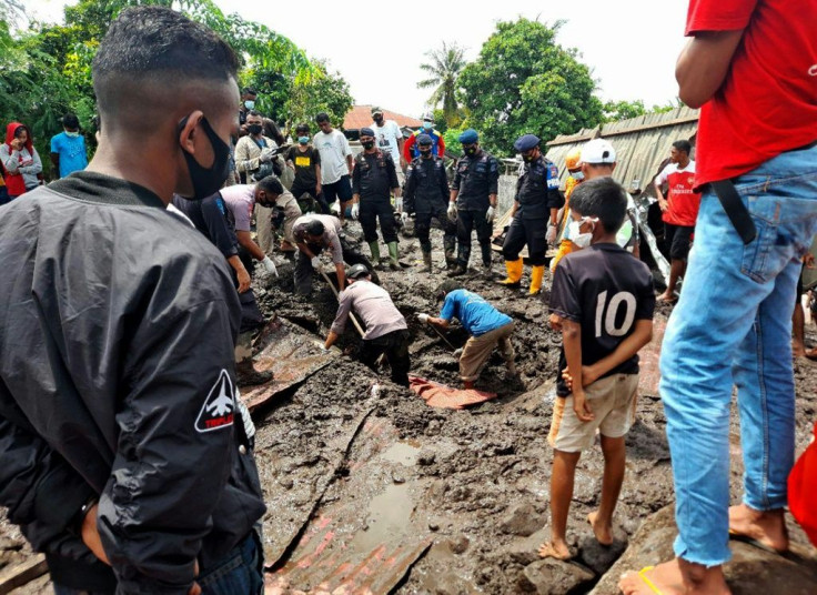 Residents watch rescuers extract mud-covered corpses from the debris in Lamanele village, East Flores, after torrehtial rains from Tropical Cyclone Seroja