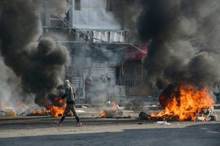An Iraqi protester walks past burning tyres during clashes with police during anti-government demonstrations in the city of Nasiriyah in January