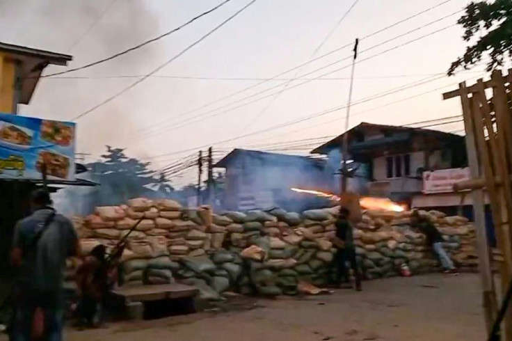 This screengrab from Hantarwadi Media video footage taken on April 9, 2021 and provided to AFPTV shows a protester setting off fireworks from behind a makeshift barricade while a man at left holds a homemade rifle during a clash with security forces durin