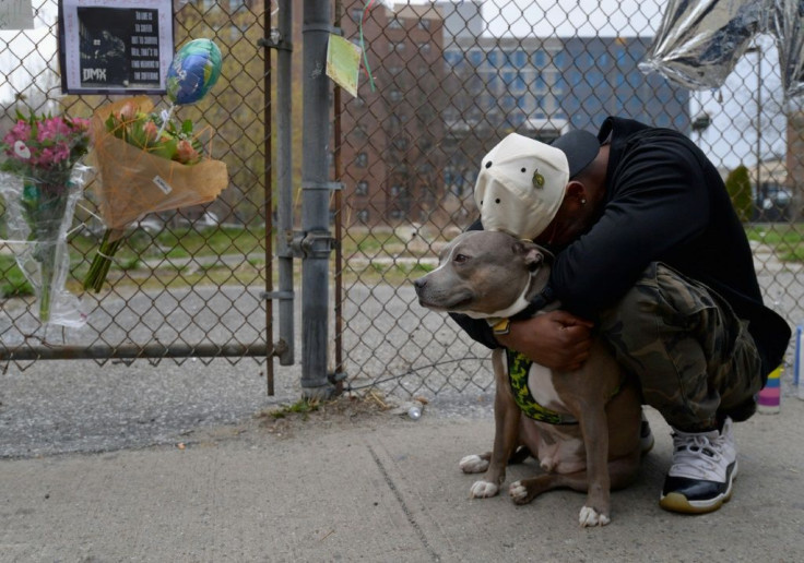A man holds his dog as he reacts at a makeshift memorial for hip-hop star DMX, who was well-known for his love of canines