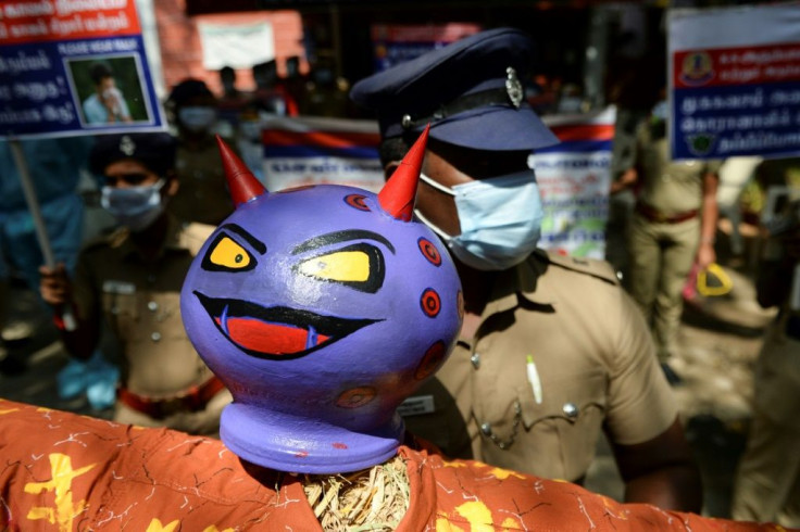 A policeman holds an effigy of a demon representing the coronavirus during an awareness campaign in Chennai, India