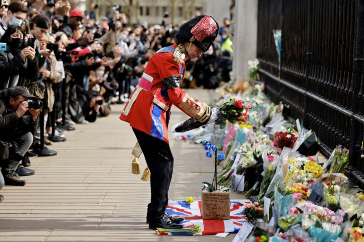 An ardent Royals fan lays a floral tribute at the front of Buckingham Palace in central London after the announcement of the death of Prince Philip