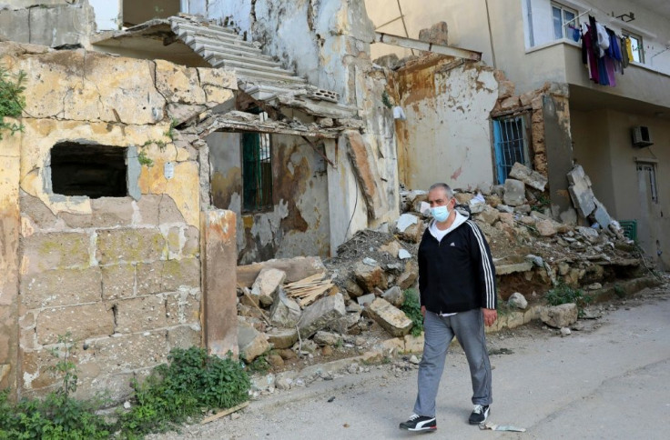 Civil war survivor Jean Saliba, walks past buildings damaged by the August 4, 2020 Beirut port blast, in Karantina district of the Lebanese capital