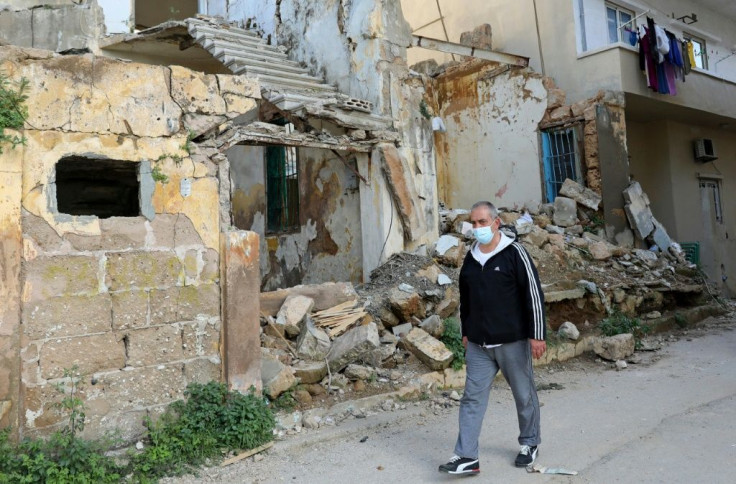 Civil war survivor Jean Saliba, walks past buildings damaged by the August 4, 2020 Beirut port blast, in Karantina district of the Lebanese capital