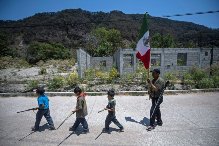 Children carry replica weapons through the Mexican village of Ayahualtempa before taking part in training in defense against drug traffickers