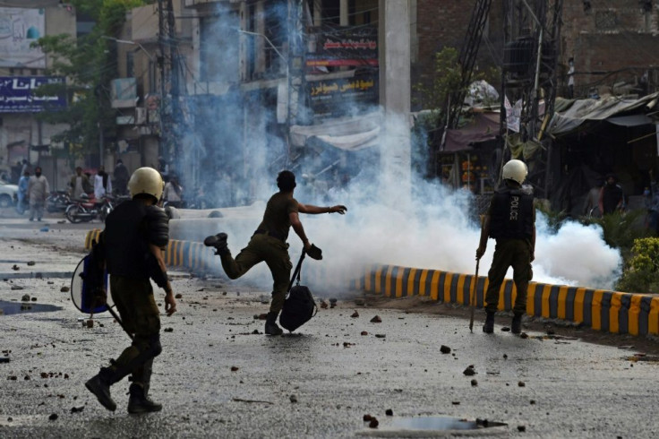 A policeman throws a stone at Tehreek-e-Labbaik Pakistan supporters during protests in Lahore