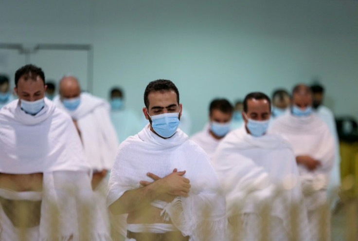 Masked Muslim pilgrims perform evening prayers in Mecca