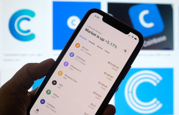 This illustration photo shows the Coinbase logo in the background as a person checks cryptocurrencies prizes on a smartphone in Los Angeles on April 13, 2021
