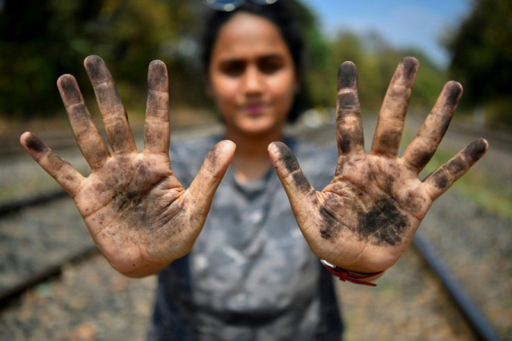 Zoologist Hycintha Aguiar shows her soot-covered hands after handling coal fallen onto railway tracks from a cargo train at the Kulem railway station in Goa