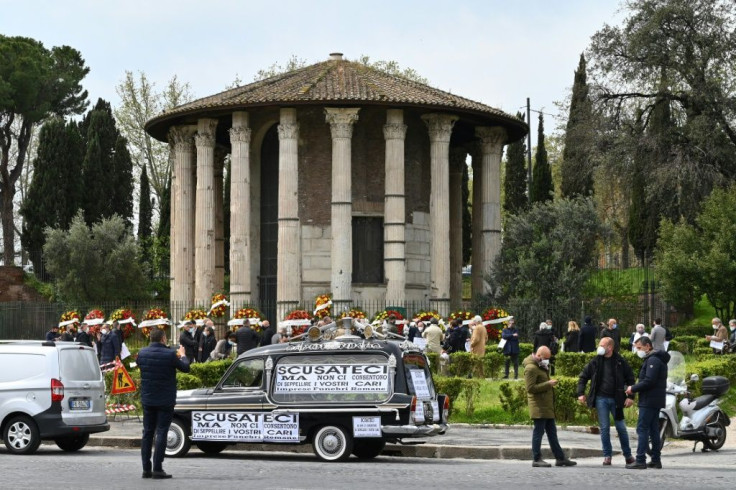 A hearse with a placard that reads "Apologies but they don't let us bury your loved ones" is parked close to funeral home workers protesting at the ancient Roman "Hercules the Winner" circular temple against the disruption of funeral services due to the i