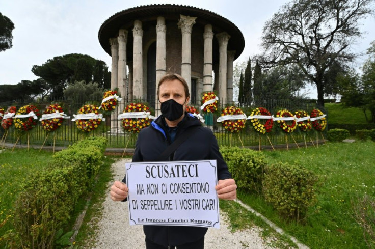Maurizio Tersigni, a Roman funeral home worker at the Sphinx, holds a banner that reads, "Apologies but they don't let us bury your loved ones" during a protest at the ancient Roman "Hercules the Winner" circular temple against the disruption of funeral s