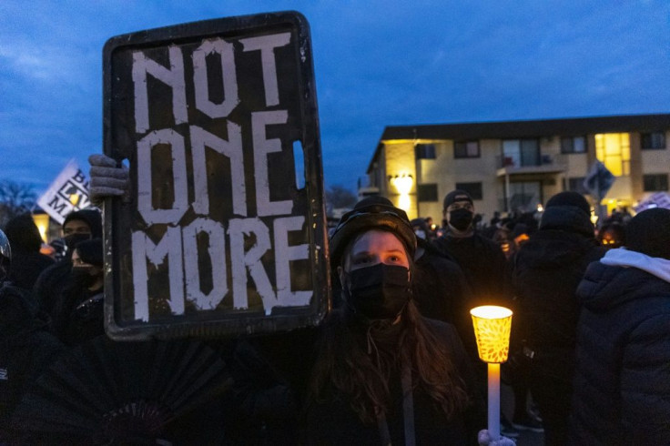 Demonstrators hold candles and signs ahead of an evening curfew in front of the Brooklyn Central Police Station outside Minneapolis, near where a policewoman shot dead Daunte Wright