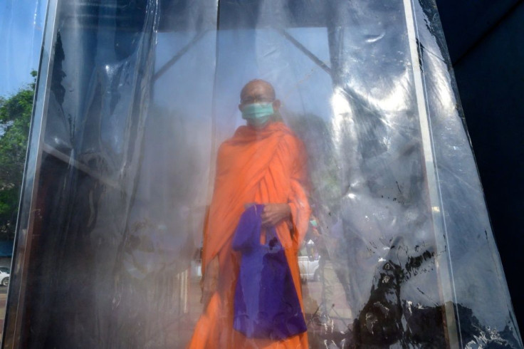 A Buddhist monk is sprayed with disinfectant in a special cabin during a mass testing event