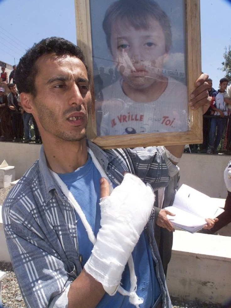 A wounded Berber man, pictured in May 2001, holds the picture of a 13-year-old boy who was shot dead in clashes in Takriet, near Bejaia, in the Kabylie region