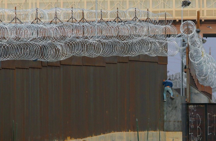 A migrant climbs the border fence in an attempt to enter the United States from the Mexican city of Ciudad Juarez