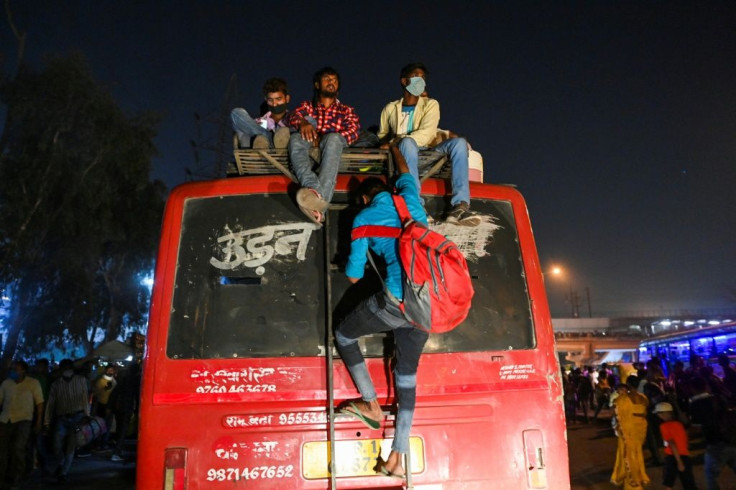People climb on the roof of one bus at a station in New Delhi in a desperate attempt to get to their hometowns