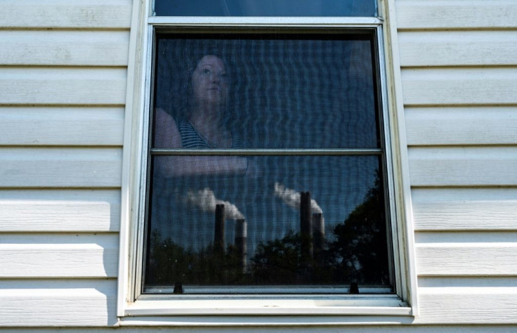 Jacey Maharrey, 27, poses for a photo as she looks at steam and exhaust from the Miller coal plant near her home in Alabama