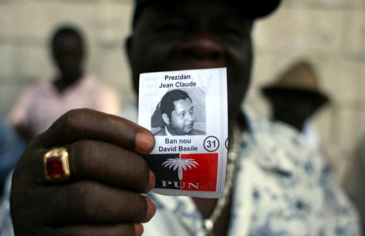 A former member of Tonton Macoute paramilitary force displays a photograph of Jean-Claude "Baby Doc" Duvalier while on guard outside a private hospital in Port-au-Prince where the ex-dictator was being treated in 2011