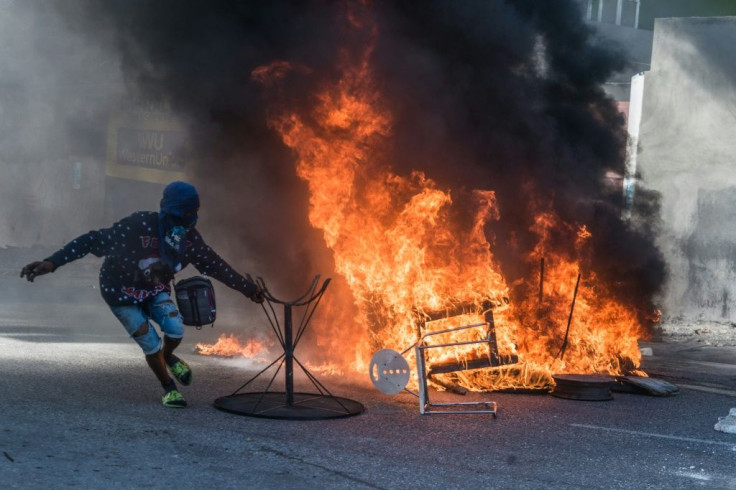 A protestor moves from the fire during a demonstration on February 14, 2021 in Port-au-Prince