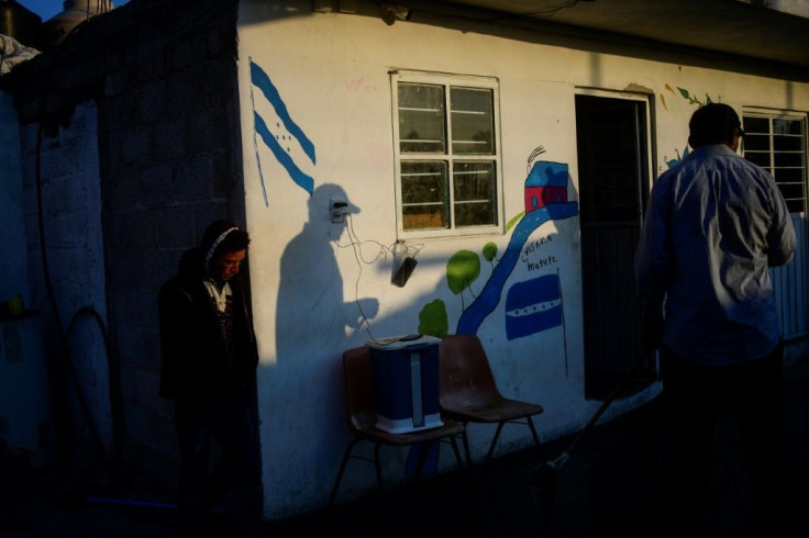 Central American migrants near a Honduran flag painted on a wall at the Sagrada Familia shelter in Mexico's Tlaxcala state as they make their way to the United States in April 2021