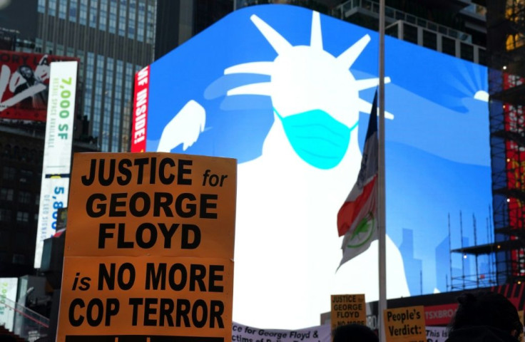 A screen shows a silhouette of the Statue of Liberty wearing a face mask as people rally in Times Square in New York City after Derek Chauvin was found guilty on all counts in the murder of George Floyd