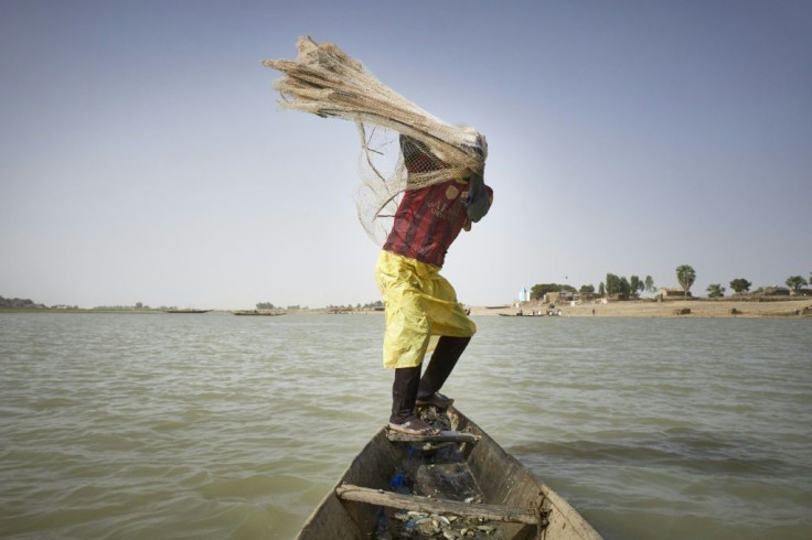 A fisherman on his pirogue throws a net in the Niger river in Mopti